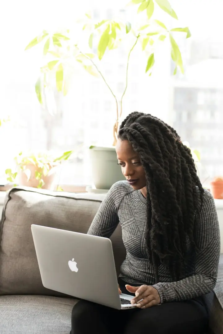 Woman working on a laptop at home beside plants