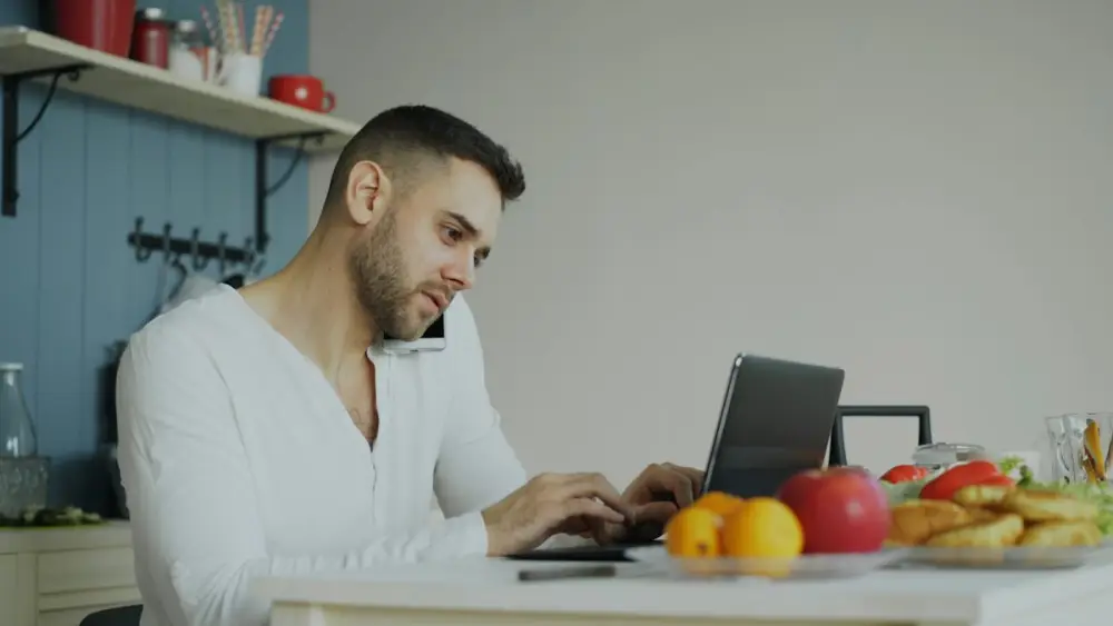 Man working on a laptop at his kitchen table